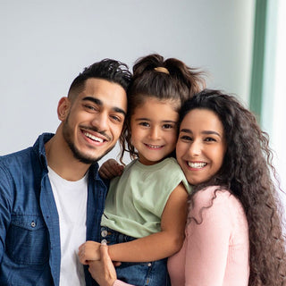 Happy parents smiling with their elementary-aged daughter, showcasing the supportive family community at Spell Well Montessori School.